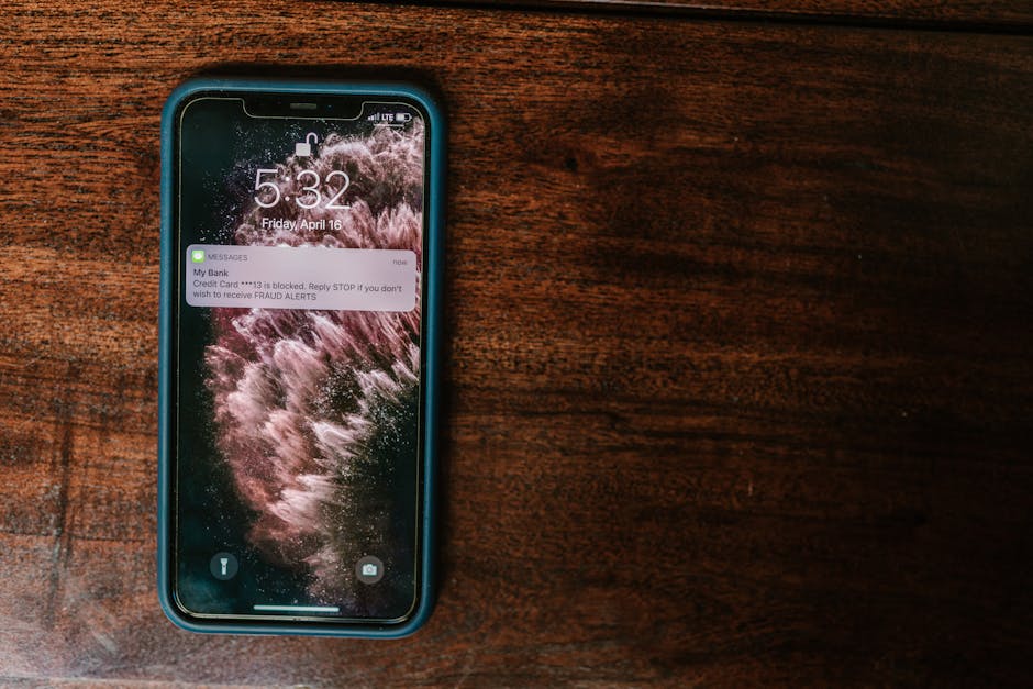Žmogus žiūri namų saugumo pranešimą telefone prie įėjimo